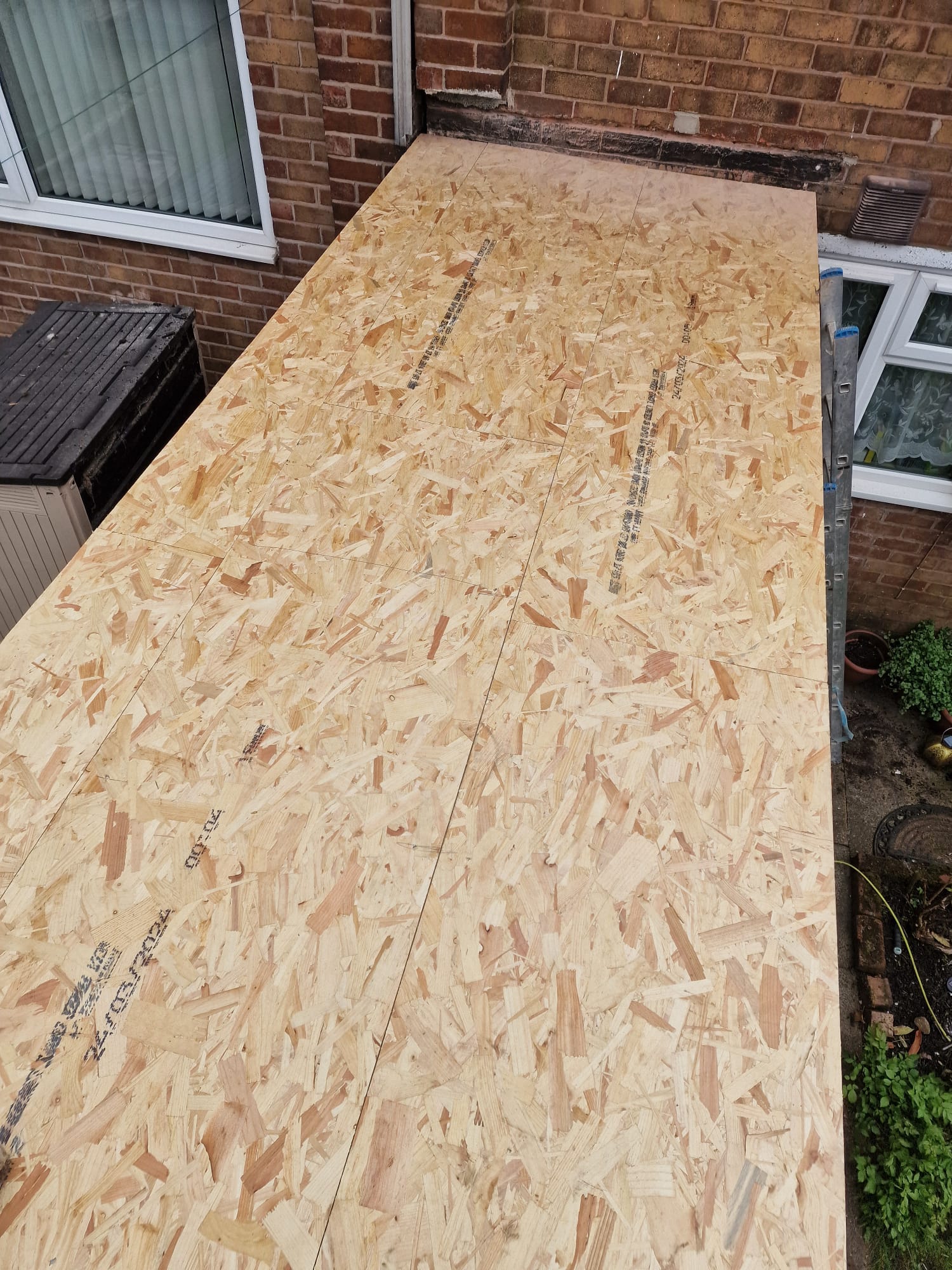 Fresh OSB timber roof deck installed on a single-storey rear roof, ready for the waterproof membrane